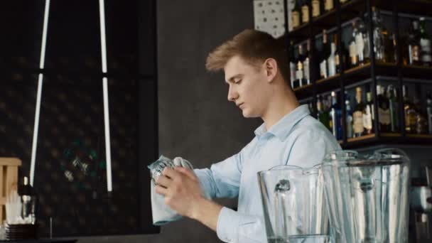 Бармен вытирает стаканы за стойкой бара — стоковое видео