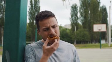 Yakışıklı adam yeme pizza bir basketbol sahası üzerinde Kapat