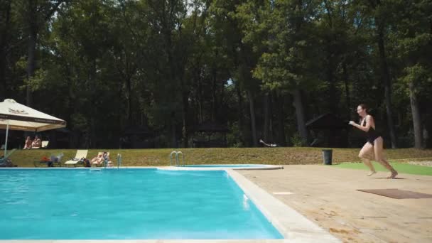 Девушка бежит и прыгает в бассейн, пикирует — стоковое видео