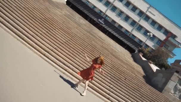 Retrato de la ciudad de una niña en un vestido baila sobre un telón de fondo de escaleras — Vídeo de stock