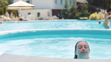 Güzel genç kadın havuzdan çıkar ve kameraya benziyor