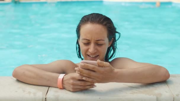 若い女性がプールでスマート フォンを使用してください。. — ストック動画