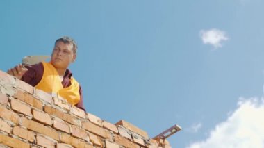 Duvarcı ustası bir mavi gökyüzü arka plan üzerinde çalışma