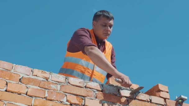 Кирпичник строит стены в соответствии со строительными планами — стоковое видео