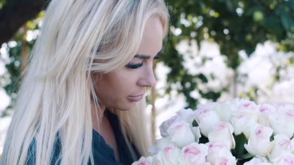 Красива дівчина з великим букетом троянд в саду — стокове відео