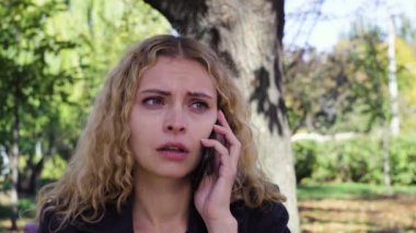 parkta bir bankta oturmuş telefonda konuşan ağlayan kız