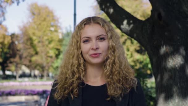 Краса молода жінка, біля дерев на вулиці восени барвистий парк — стокове відео