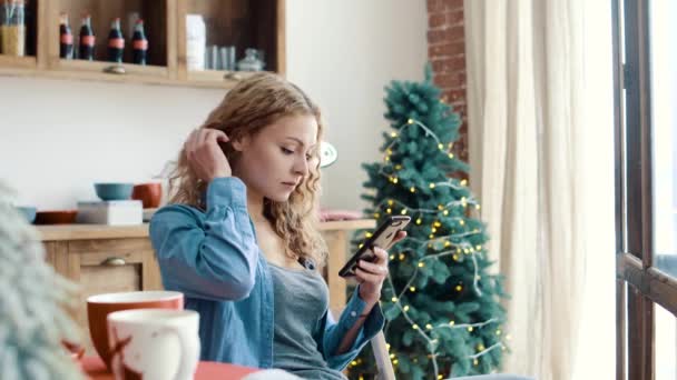 Ragazza digitando un messaggio nello smartphone al mattino in cucina — Video Stock