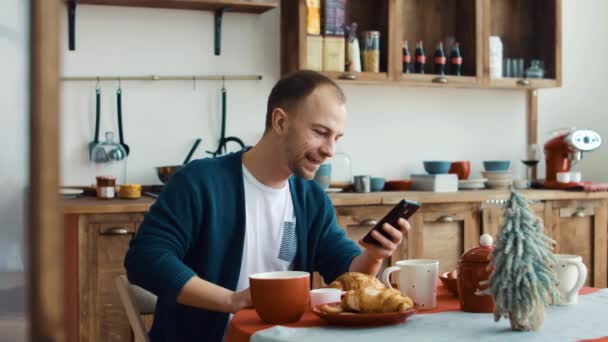 Man använder telefon samtidigt ha kopp kaffe i köket på hem 4k — Stockvideo