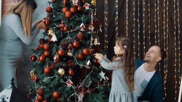 Het kleine meisje, papa en zwangere moeder in de buurt van de kerstboom — Stockvideo