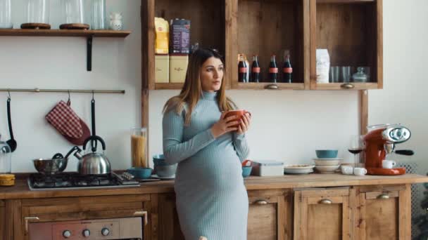 Pregnant woman in the kitchen drinking coffee — Stock Video