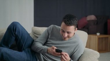 Telefon ile kanepede yatan adam gülüyor