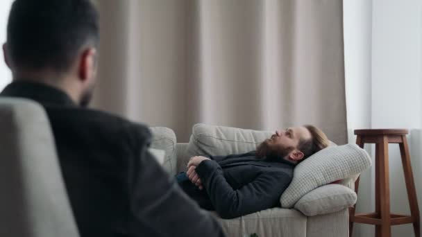 Um homem está deitado num sofá numa recepção de psicoterapeutas. — Vídeo de Stock