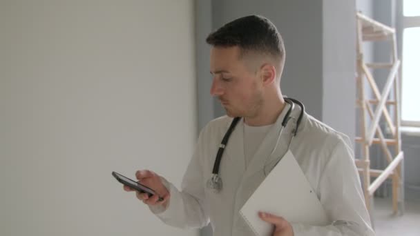De dokter is op de telefoon in de hal van het ziekenhuis — Stockvideo