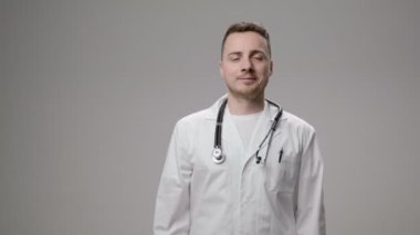 Mutlu genç beyaz doktor başparmak gösterilmesini