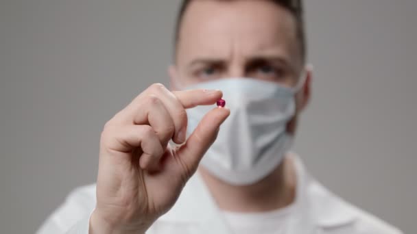 Молодой доктор в маске с таблеткой — стоковое видео