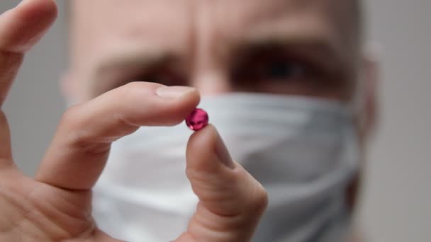 Unga läkare i mask undersöker ett piller — Stockvideo
