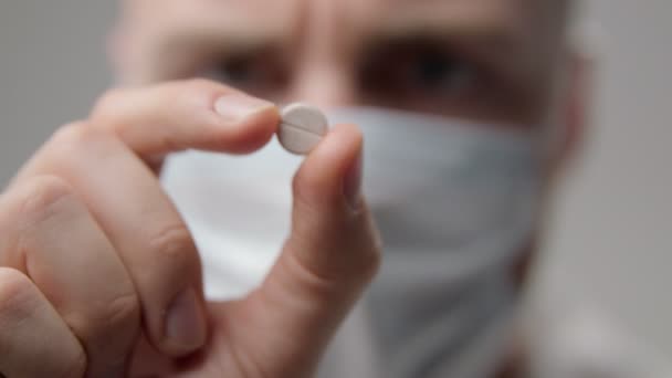 Jeune médecin masqué examine une pilule — Video