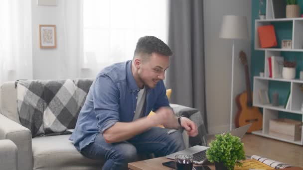 Man Sitting at Sofa and Using Laptop and Celebrates Win — Stock Video