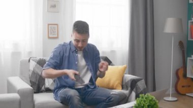Young man with tv remote playing on invisible air drums