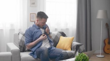 Elinde bir tv uzaktan kumandaile görünmez bir gitar çalan yakışıklı adam