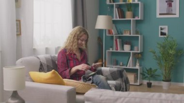 Kanepede oturan ve telefonda örgü talimatları izlerken kadının Pan çekim