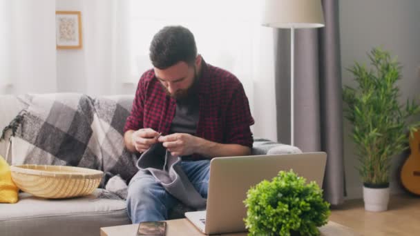 Colpo palmare di uomo seduto sul divano e imparare a lavorare a maglia — Video Stock