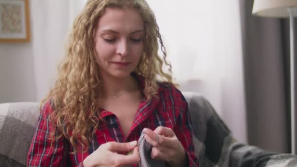 Handheld tilt shot of woman knitting crochet clothes in cozy home — Stock Video