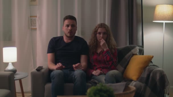 Zoom in shot of couple living room late at night watching a scary horror film — Stok video