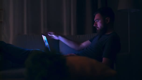 Mittlere Aufnahme eines jungen Mannes, der seinen Laptop öffnet und nachts nach Hause tippt — Stockvideo