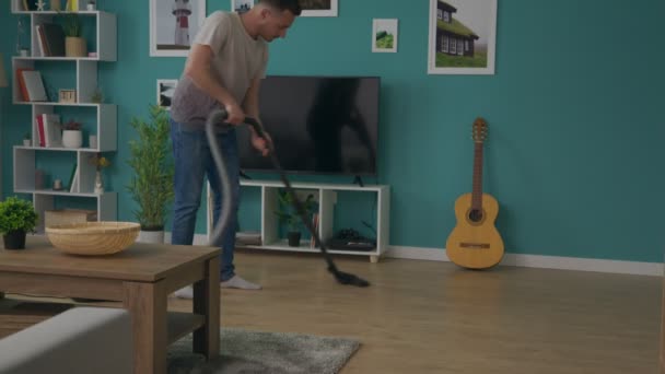 Κλίση προς τα επάνω shot του Man καθαρίζοντας το σπίτι με ηλεκτρική σκούπα — Αρχείο Βίντεο