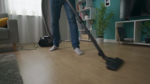 Handpfanne fotografiert Mann, der gemütliche Wohnung mit Staubsauger reinigt — Stockvideo