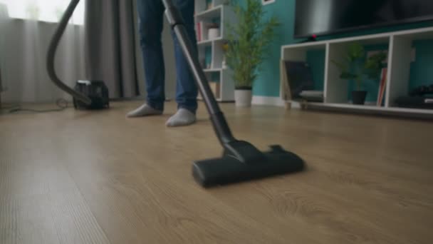 Handheld-Nahaufnahme von Mann, der gemütliche Wohnung mit Staubsauger reinigt — Stockvideo