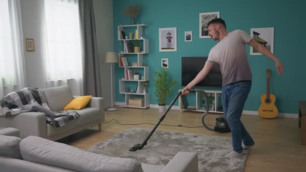 Seorang pria Vacuums sebuah apartemen nyaman dan menari menyenangkan — Stok Video