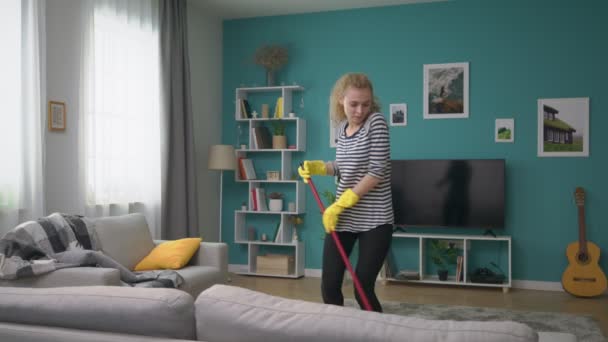 Breed shot van de vrouw schoon de vloer in gezellig appartement en dansen — Stockvideo