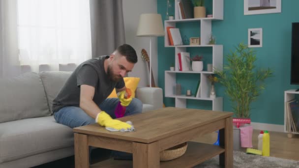 Handschuss eines Mannes wischt Staub auf dem Couchtisch in seinem gemütlichen Wohnzimmer — Stockvideo