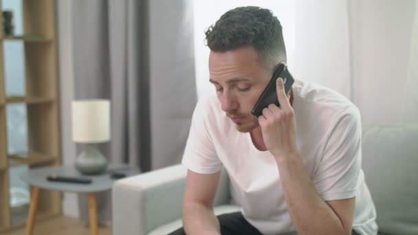 Man zittend op de bank bellen op de smartphone thuis — Stockvideo