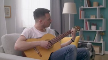 Genç adamın el çekim onun rahat oturma odasında gitar çalar.
