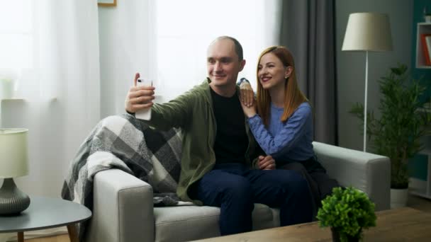 Young man taking selfie on phone camera with his girlfriend in the living room — Stock Video