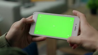 Bir adam oturma odasında yeşil ekranda bir video izler