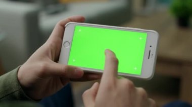 Bir adam oturma odasında yeşil ekran ile bir akıllı telefon bir karakter seçer