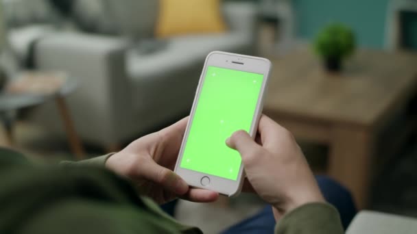 Mãos masculinas usando um telefone com uma tela verde na sala de estar — Vídeo de Stock