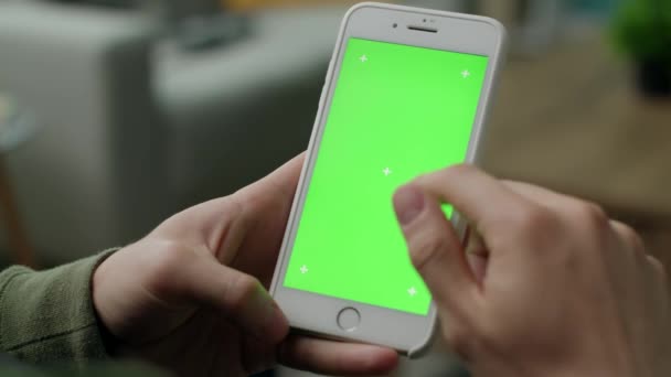 Manos masculinas usando un teléfono con una pantalla verde en la sala de estar — Vídeos de Stock