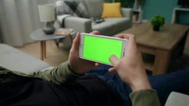 Yeşil Mock-up Ekran ile Smartphone kullanarak Bir Kanepede Evde Man Sitng