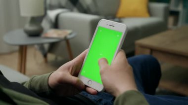 Yeşil Mock-up Ekran ile Smartphone kullanarak Bir Kanepede Evde Man Sitng