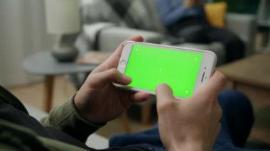 Yeşil Mock-up Ekran ile Smartphone kullanarak Bir Kanepede Evde Man Sitng