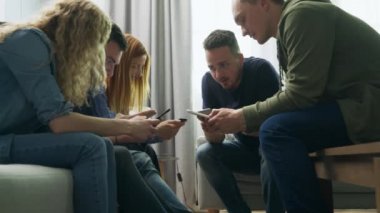 Bir grup arkadaş oturma odasında akıllı telefon kullanıyor.