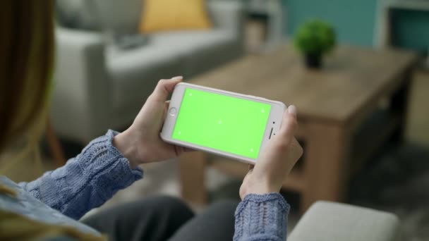 Mulher em casa sentado em um sofá usando com verde Mock-up Screen Smartphone — Vídeo de Stock