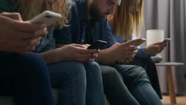 Un grupo de amigos usa teléfonos inteligentes en la sala de estar — Vídeo de stock