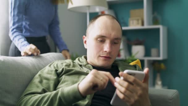 Menina e namorado usam smartphone no sofá juntos — Vídeo de Stock